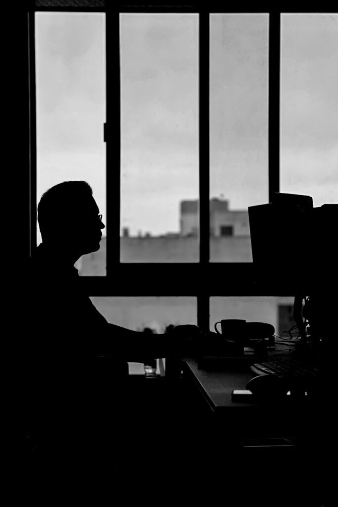 Silhouette of a person working at a window desk