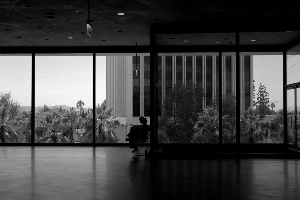 A person in silhouette before large windows