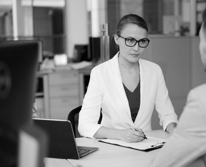 An interviewer taking notes across a desk