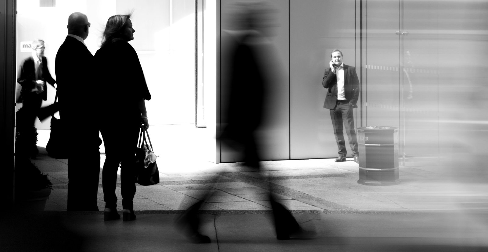 Silhouettes of people walking through a bright modern lobby